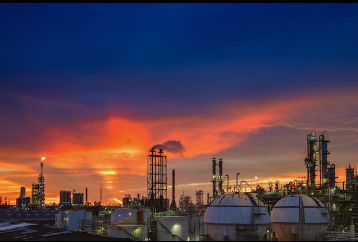 Industrial refinery at sunset, distillation columns and storage spheres in silhouette